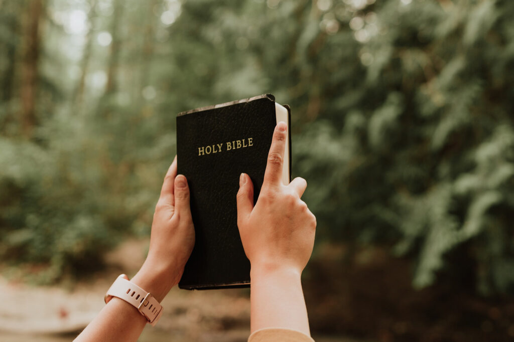 woman_holding_bible_up_towards_the_trees